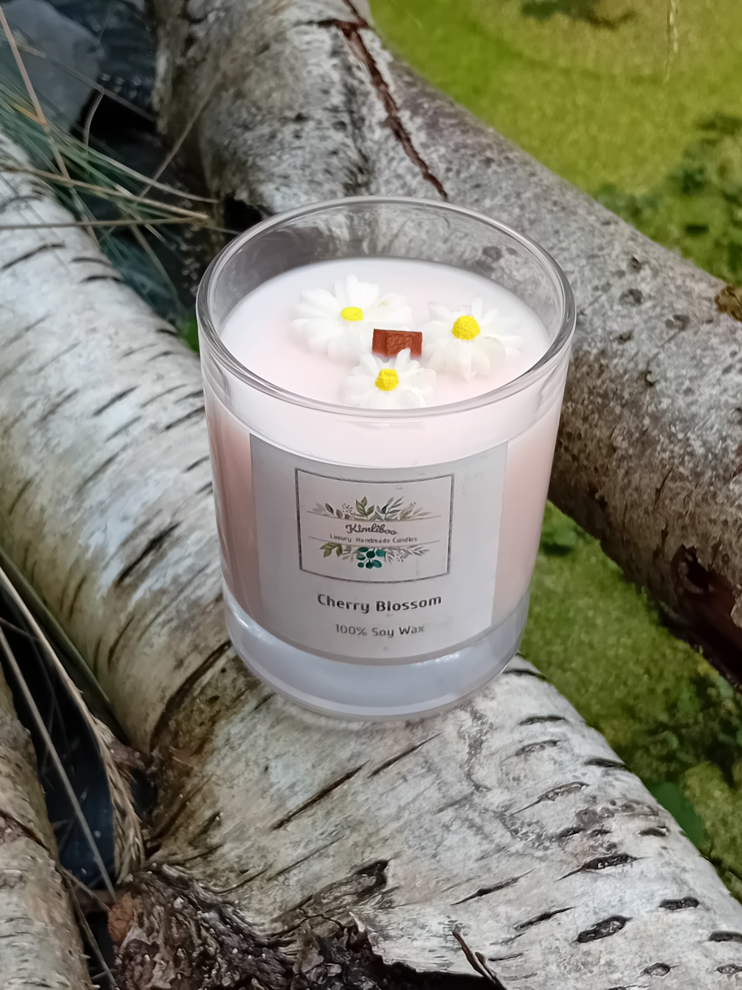 Pink candle with daisy decorations on a tree branch