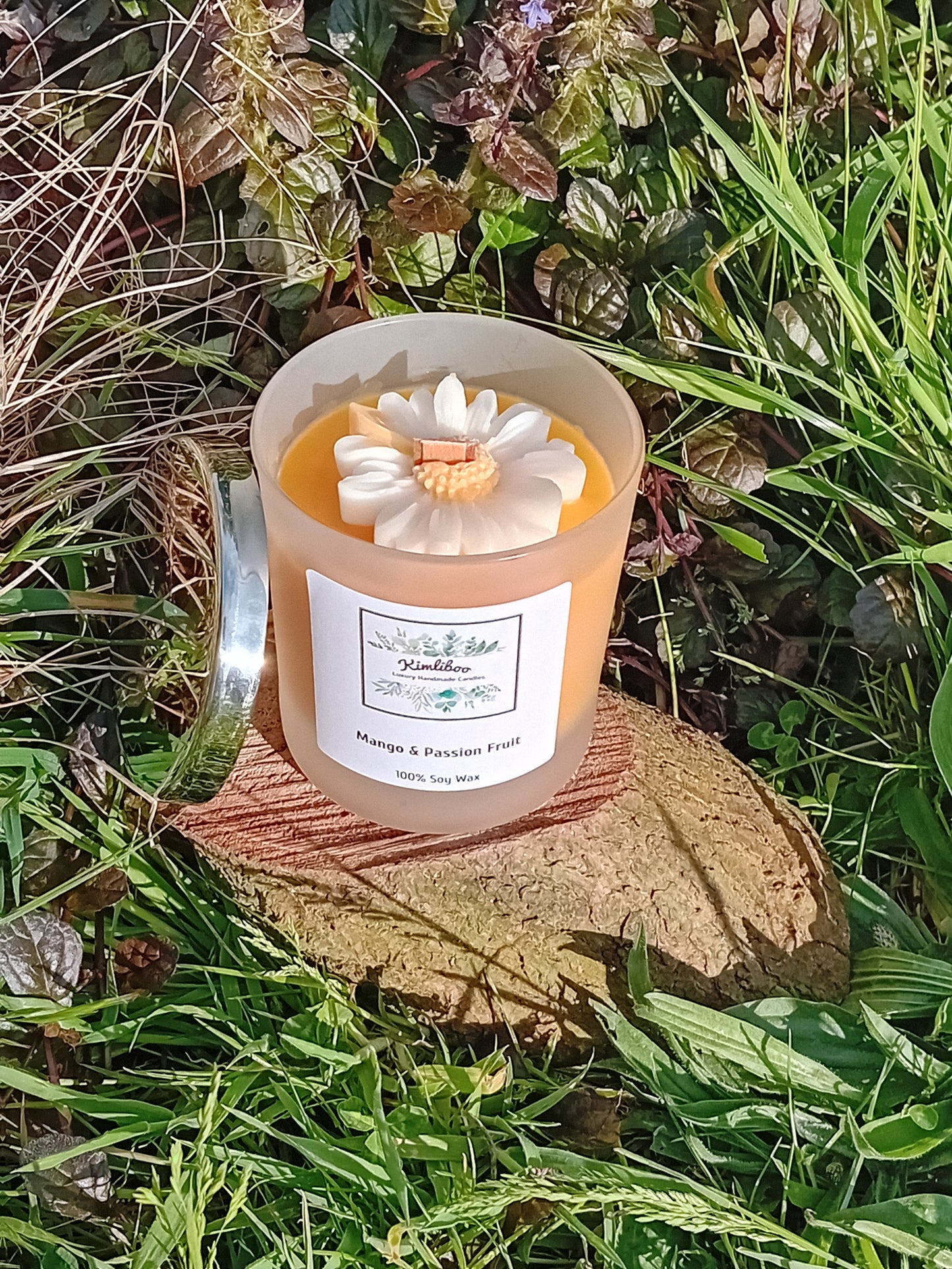 Mango & Passion Fruit fragranced orange candle in a 30cl frosted jar with wooden wick and a large daisy-shaped wax decoration.