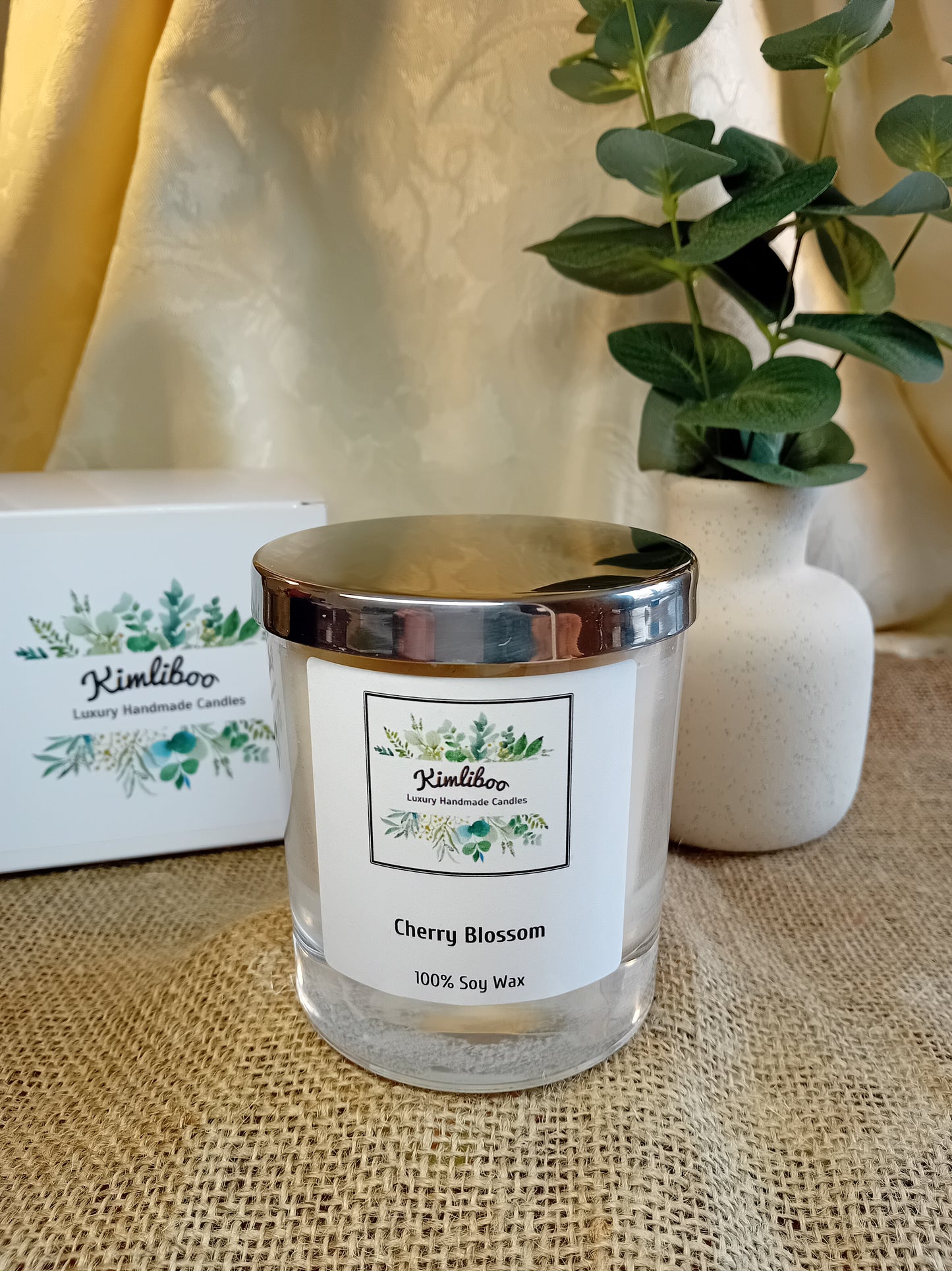 White fragranced candle with silver lid and white presentation box.