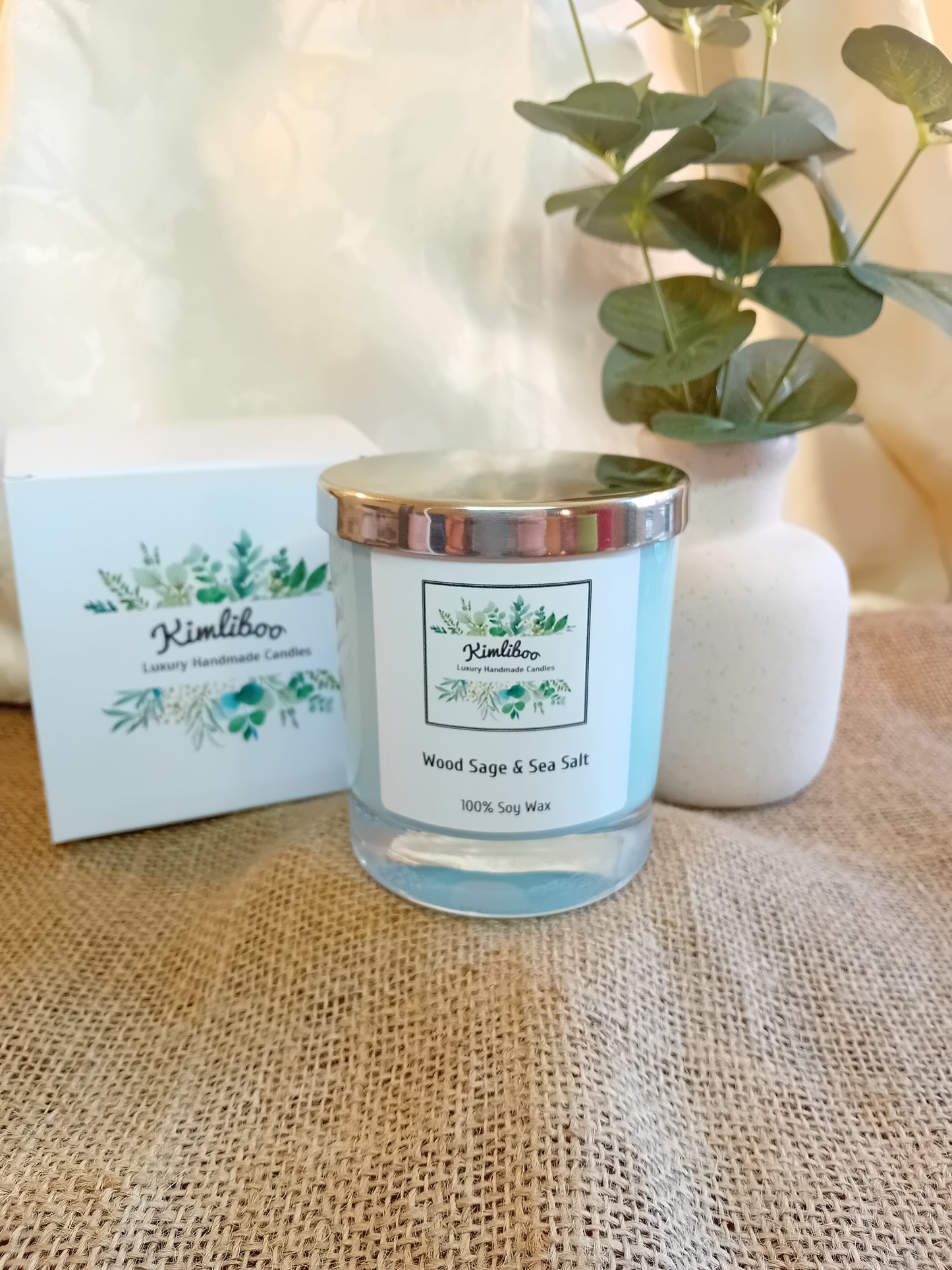 Wood Sage & Sea Salt fragranced light blue candle with silver lid and white presentation box.