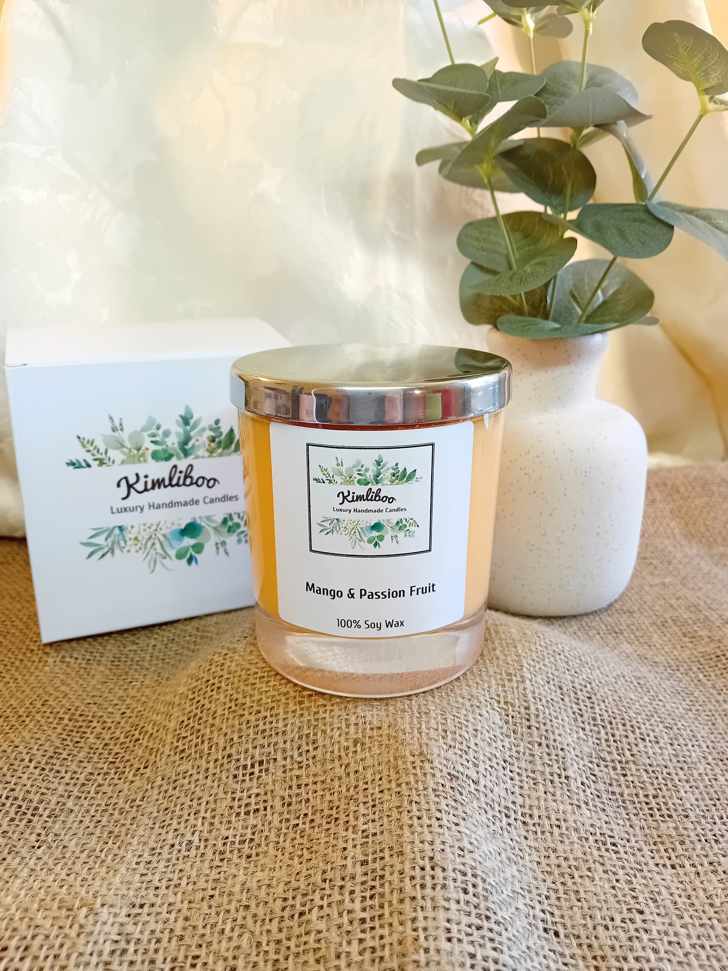 Mango & Passion Fruit fragranced orange candle with silver lid and white presentation box.