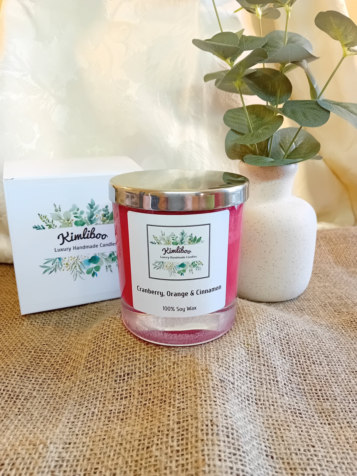 Cranberry, Orange & Cinnamon fragranced deep red candle with silver lid and white presentation box.