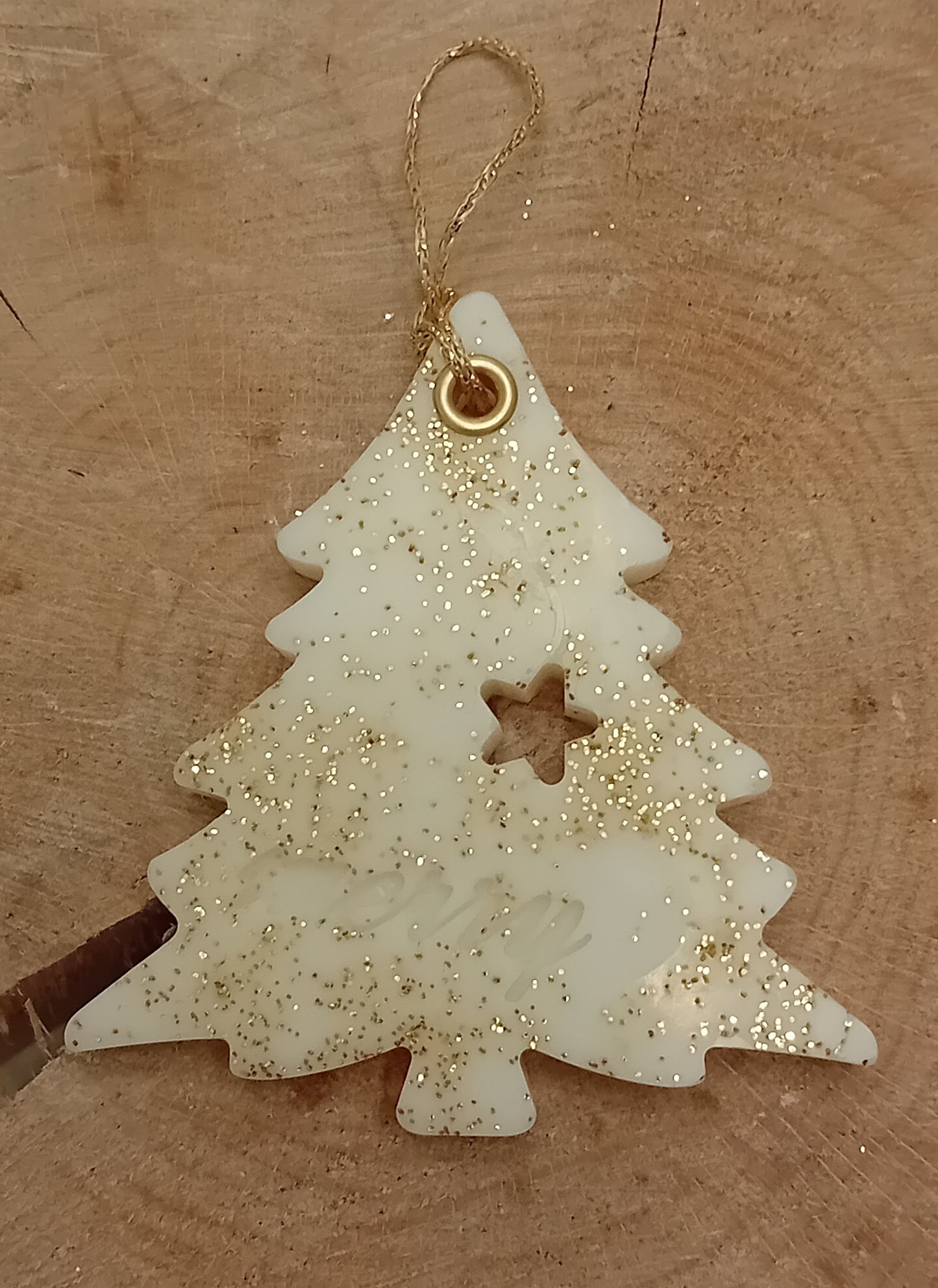 Christmas tree shaped wax sachet decorated with gold glitter on a wooden log slice background.