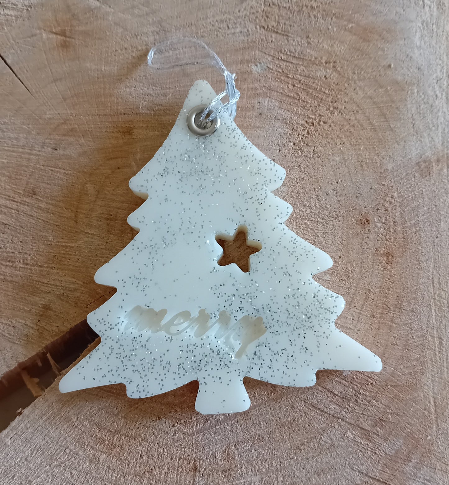 Christmas Tree shaped wax sachet decorated with silver glitter with a wooden log slice background.