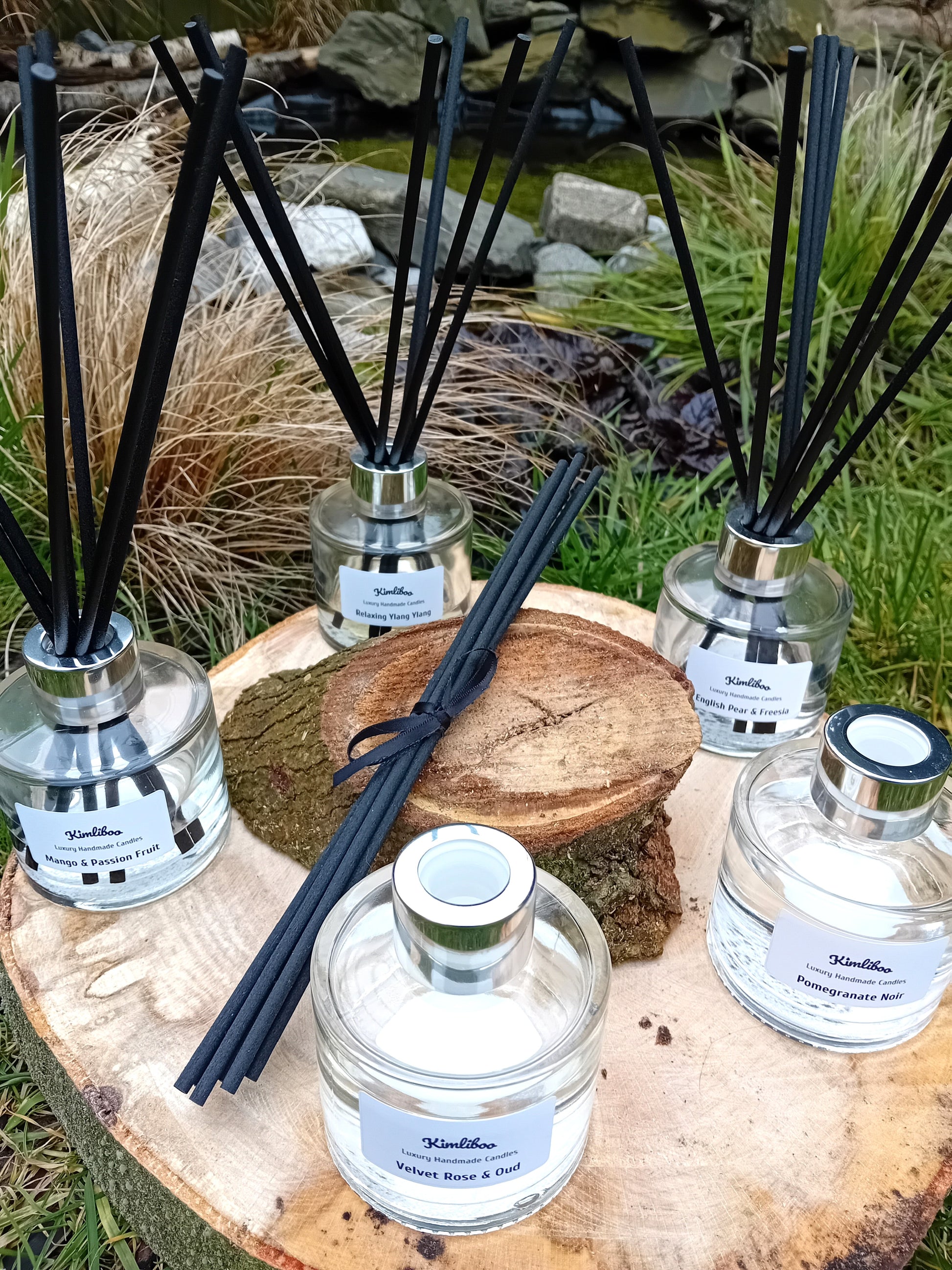 Five fragranced reed diffusers in clear, 100ml glass jars and black fibre reeds.