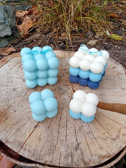 Blue and white bubble shaped candles on a wooden surface with grass in the background