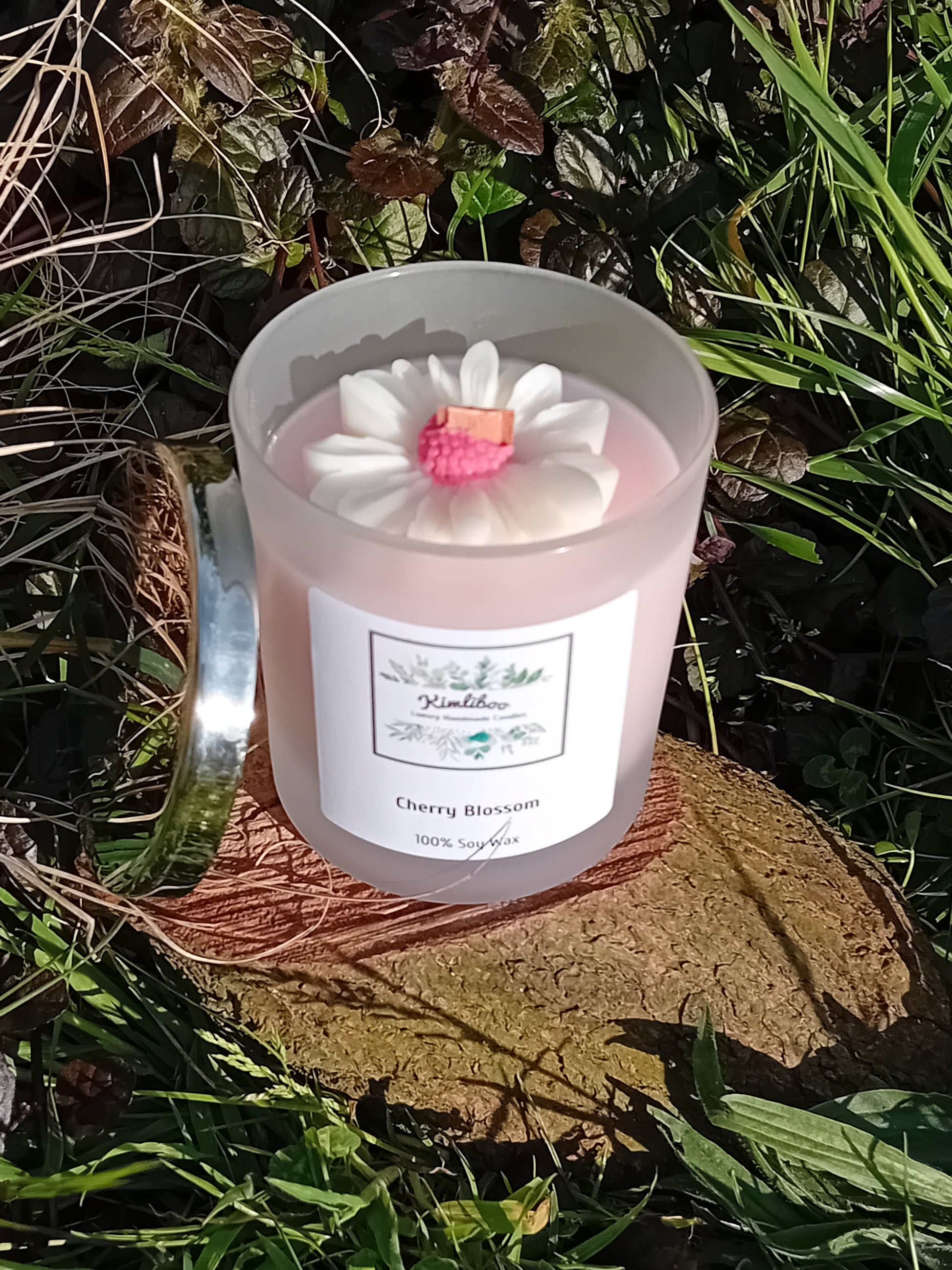 Cherry Blossom fragranced light pink candle in a 30cl frosted jar with wooden wick and a large daisy-shaped wax decoration. 