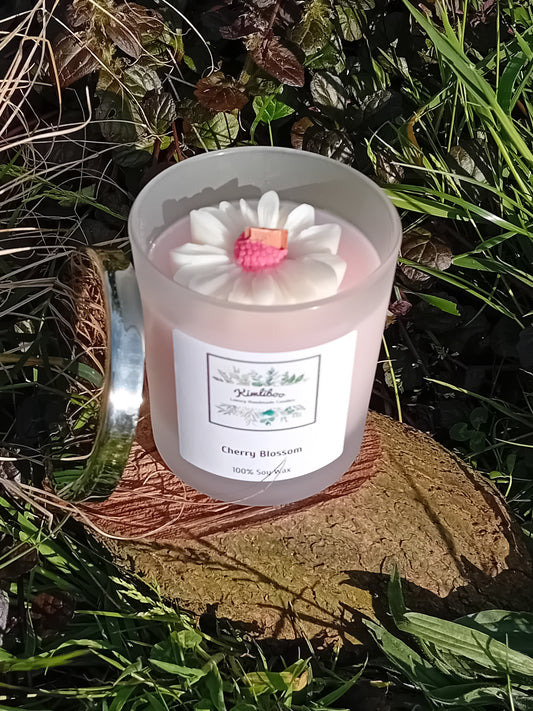 Cherry Blossom fragranced light pink candle in a 30cl frosted jar with wooden wick and a large daisy-shaped wax decoration. 