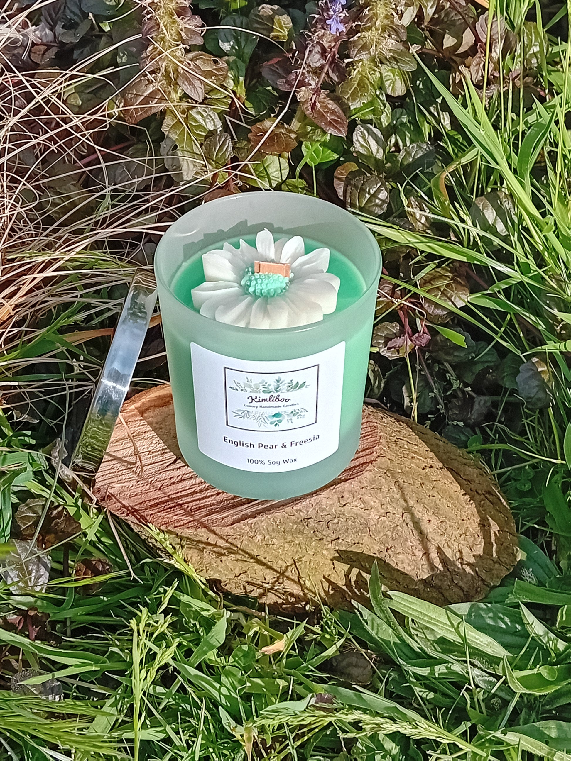 English Pear & Freesia fragranced green candle in a 30cl frosted jar with wooden wick and a large daisy-shaped wax decoration. 