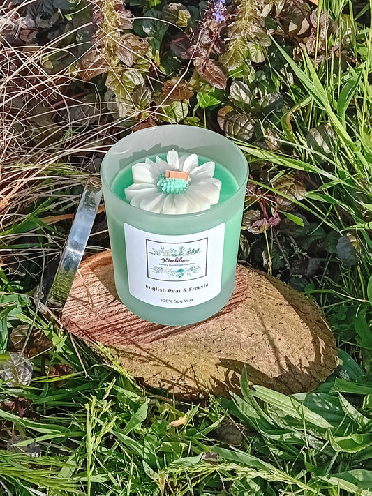 English Pear & Freesia fragranced green candle in a 30cl frosted jar with wooden wick and a large daisy-shaped wax decoration. 