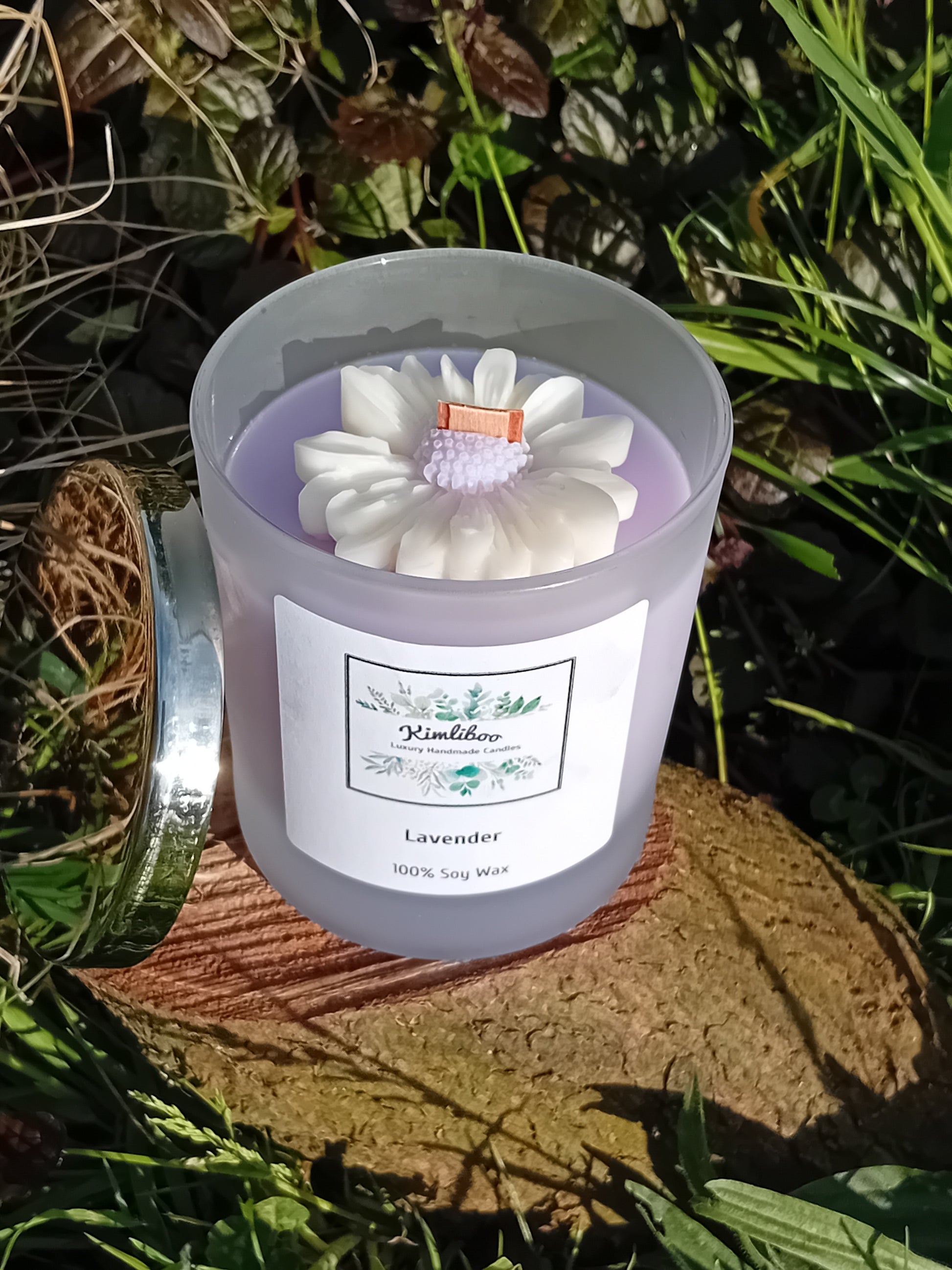 Lavender fragranced lilac candle in a 30cl frosted jar with wooden wick and a large daisy-shaped wax decoration. 