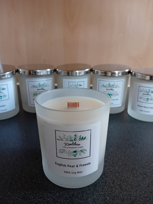 Frosted jar of English pear & freesia scented wax with a wood wick and a label, on a dark surface.