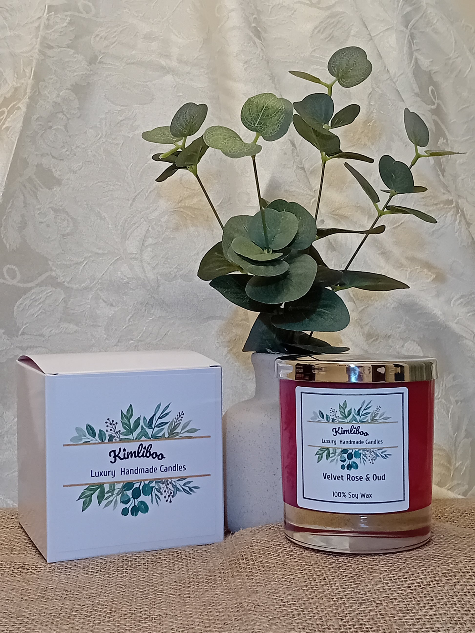 Deep red candle in a glass jar with a silver lid and a white gift box.