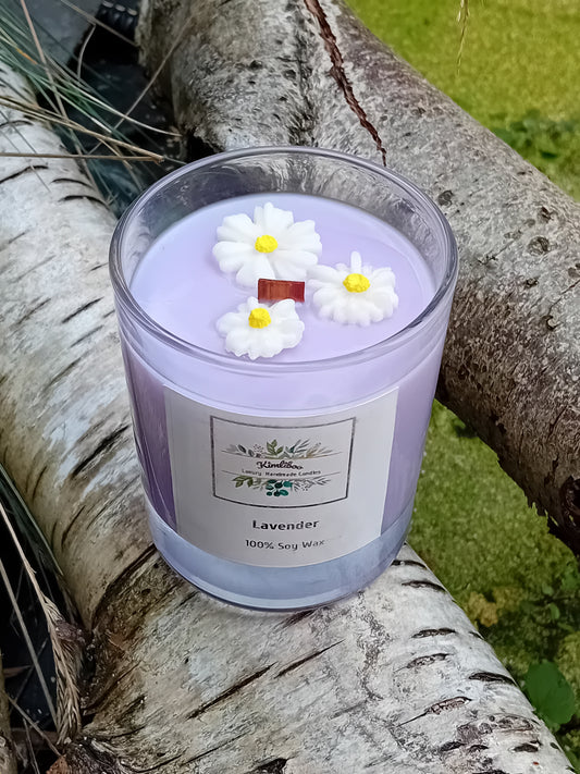 Lilac candle with daisy decorations on a tree branch