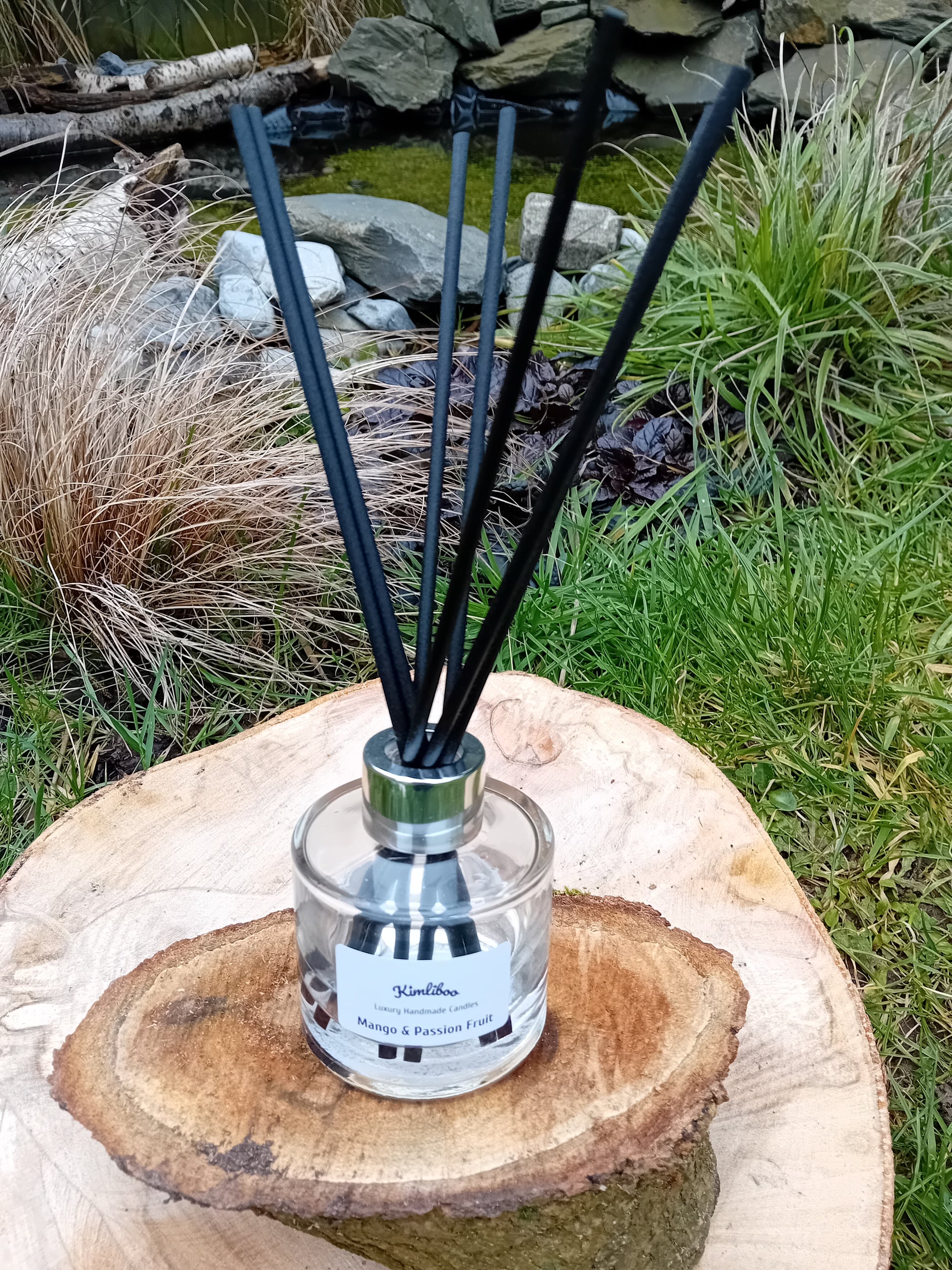 Mango & Passion Fruit fragranced reed diffuser with a 100ml clear glass jar and a bundle of black fibre reeds. 
