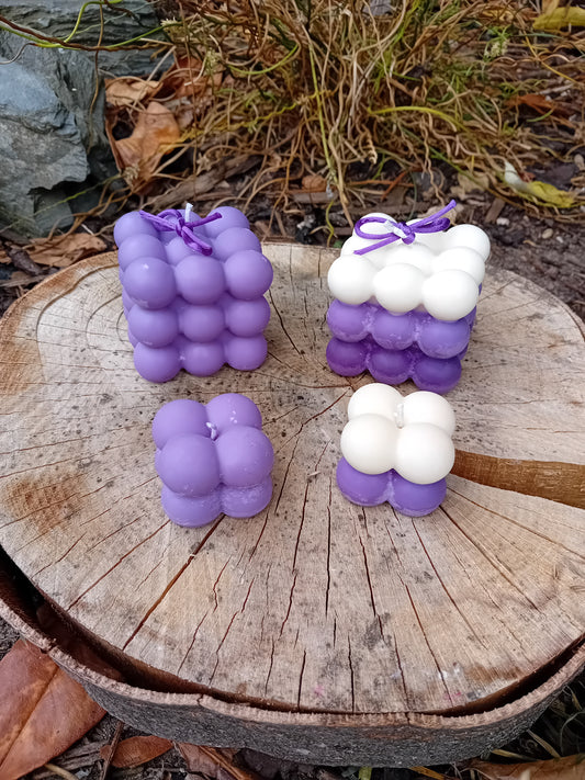 Purple and white bubble-shaped candles on a wooden surface with natural background