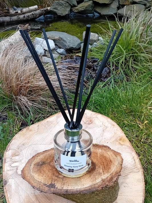 Relaxing Ylang Ylang fragranced reed diffuser with a 100ml clear glass jar and a bundle of black fibre reeds. 