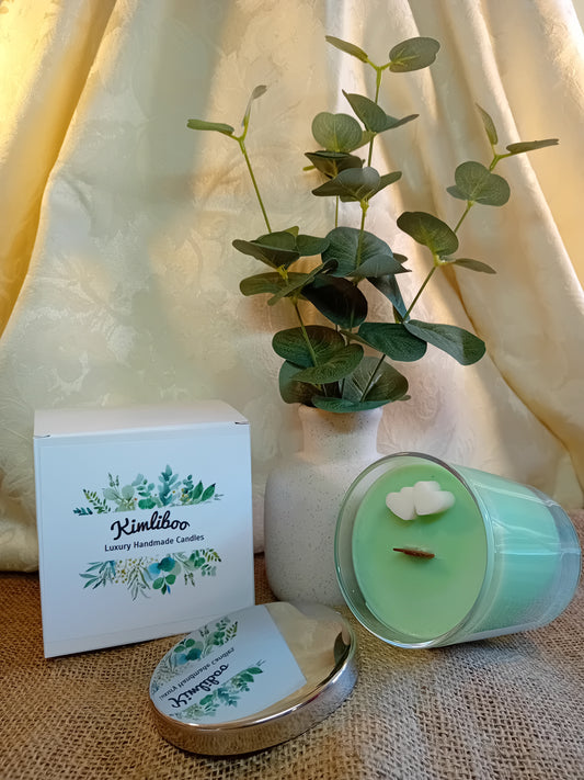 English Pear & Freesia fragranced green candle with wooden wick and two white heart-shaped wax decorations.