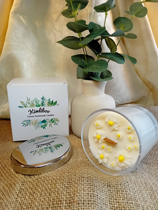 White fragranced candle with wooden wick and delicate daisy wax decorations.