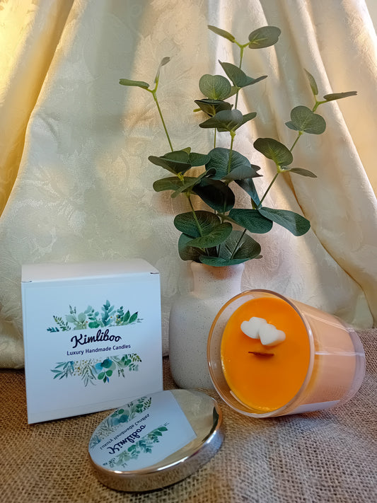 Mango & Passion Fruit fragranced orange candle with wooden wick and two white heart-shaped wax decorations. 