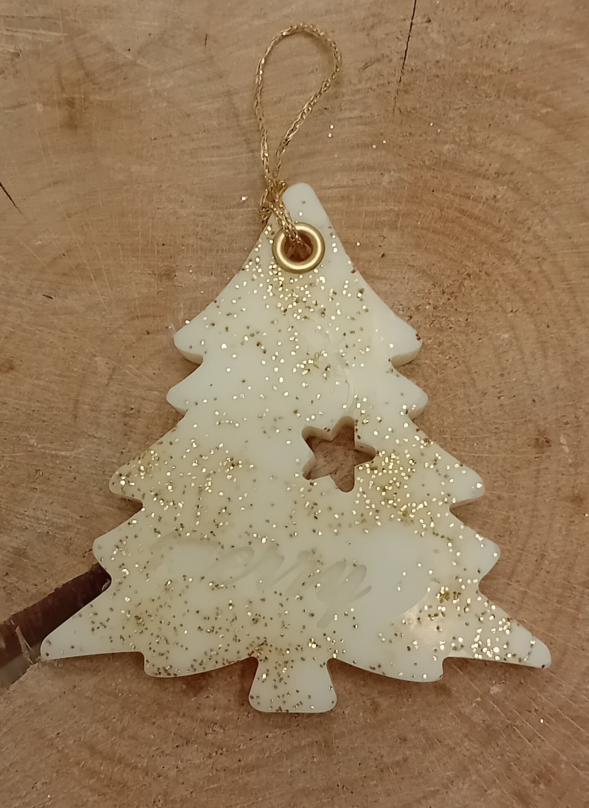 Christmas tree shaped wax sachet decorated with gold glitter on a wooden log slice background.