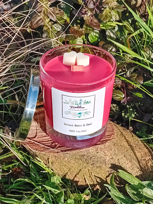 Velvet Rose & Oud fragranced deep red candle with wooden wick and two heart-shaped wax decorations. 